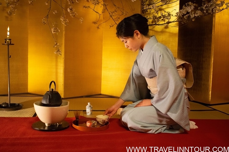 Traditional Japanese tea ceremony in Kyoto; woman in kimono preparing tea with ceremonial utensils, showcasing cultural experience on a 2-day itinerary.