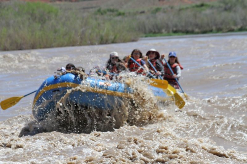 Group of people white water rafting on a river in Utah, showcasing adventure activities for nature lovers.
