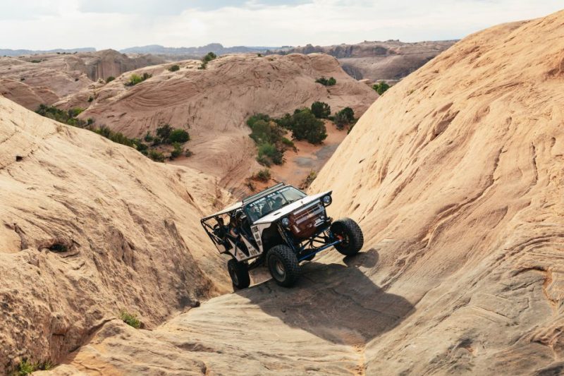 Off-road vehicle navigating the rugged terrain of Utah's sandstone landscape, ideal for outdoor adventure enthusiasts seeking thrilling activities in nature.