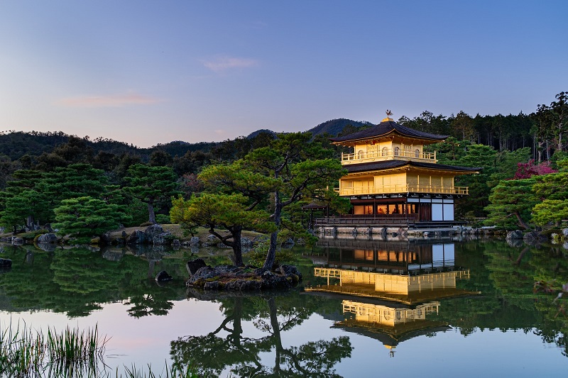 Kinkaku-ji Temple at sunset with a serene reflection in the surrounding pond, highlighting traditional Japanese architecture and lush garden setting, part of the ultimate Kyoto itinerary.