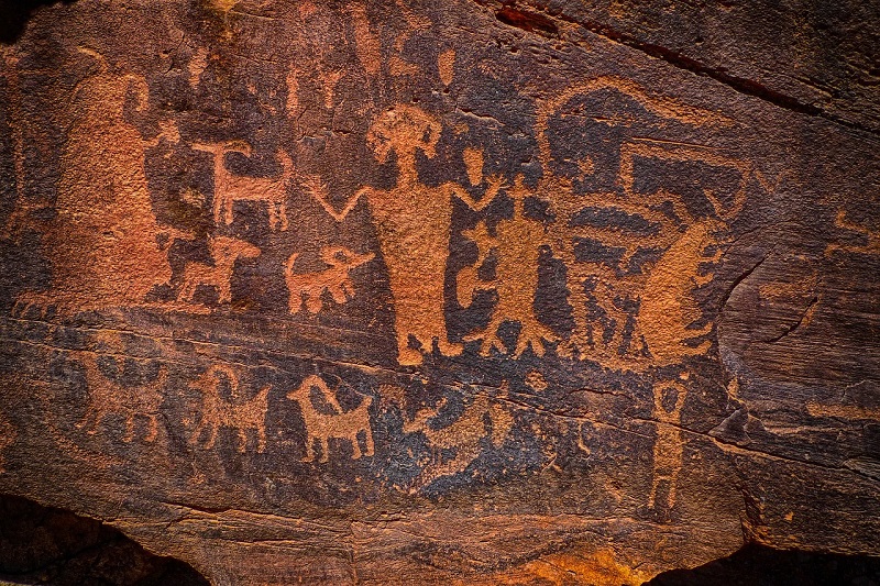 Ancient petroglyphs on a rock wall in Utah, depicting human and animal figures, showcasing rich cultural history and outdoor exploration opportunities for nature lovers.
