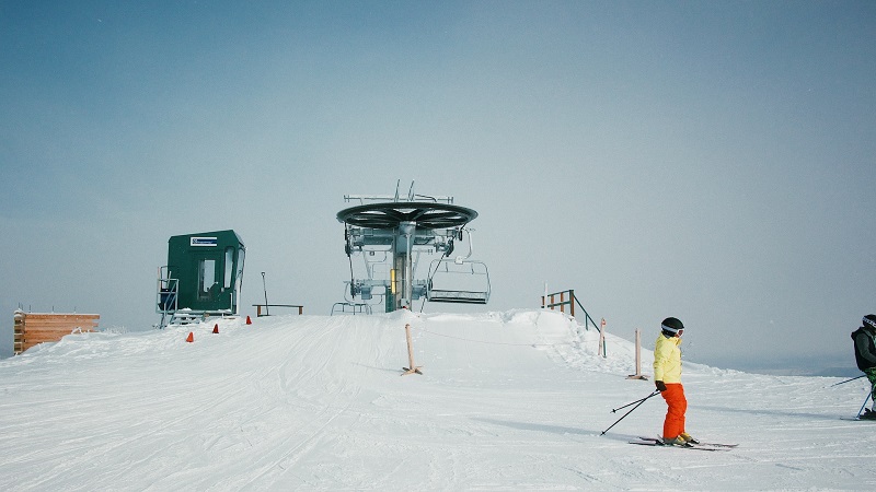 Skier in vibrant clothing at a snowy ski lift in Utah, representing outdoor adventure and winter sports activities.