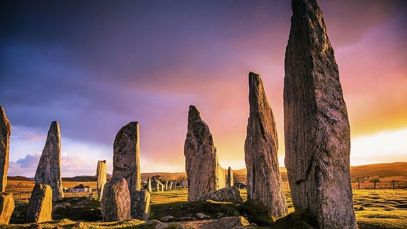 Callanish Standing Stones on Isle of Lewis at sunset, showcasing dramatic skies and historical landmarks, perfect for exploring Scottish island heritage.