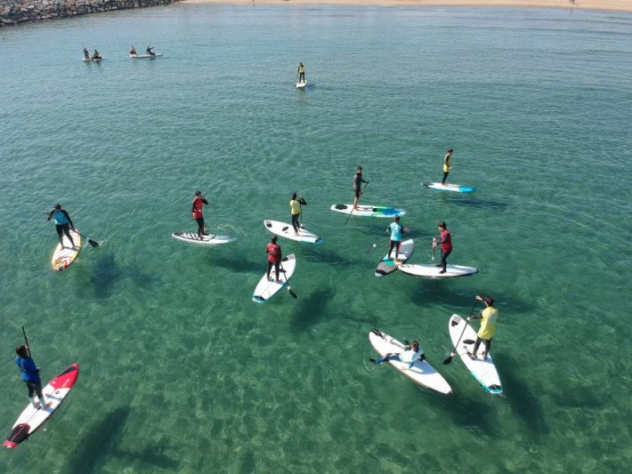Group of people paddleboarding on clear waters in Valencia, showcasing one of the city's popular outdoor activities and beautiful beaches.