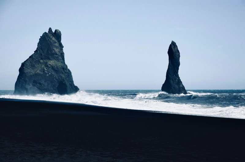 Reynisdrangar sea stacks at Reynisfjara black sand beach in Iceland, showcasing stunning natural rock formations and dramatic waves against the North Atlantic Ocean backdrop.