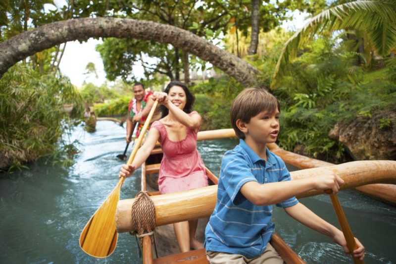 Family enjoying a canoe ride in Kona, Hawaii, surrounded by tropical greenery, highlighting cultural experiences and top attractions.