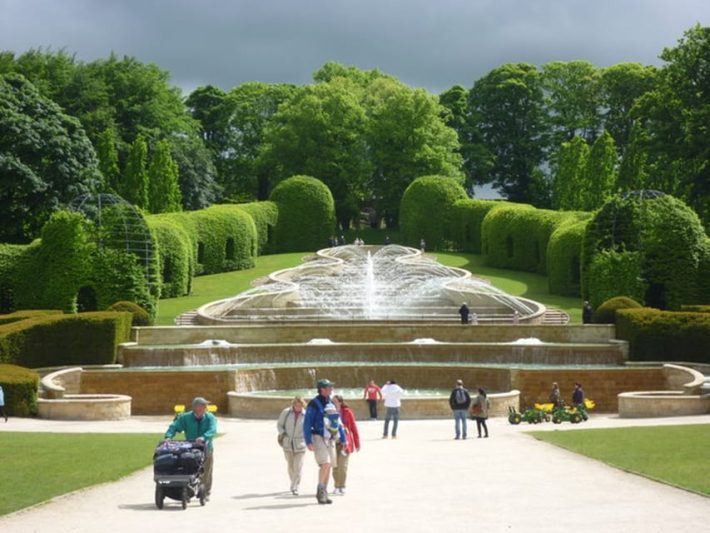 Alnwick Poison Garden, UK: Visitors strolling and enjoying the scenic view of the garden with its famous fountains, lush greenery, and educational tours on forbidden plants.