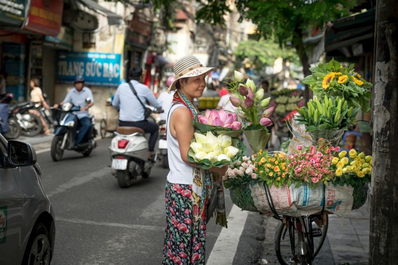 woman standing and looking on petaled flowers on street